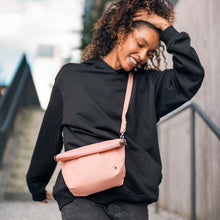 Load image into Gallery viewer, Woman carrying the Pacsafe Citysafe CX Anti-Theft Convertible Crossbody color Rose made with ECONYL® regenerated nylon
