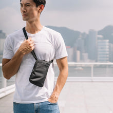 Load image into Gallery viewer, Man travelling with the Pacsafe Daysafe Anti-Theft Tech Crossbody color Black made with ECONYL® regenerated nylon
