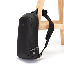 Load image into Gallery viewer, Side view of the Pacsafe Vibe 325 Anti-Theft Sling Pack color Black made with ECONYL® regenerated nylon locked to a chair

