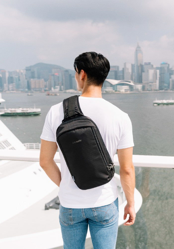 Man travelling with the Pacsafe Vibe 325 Anti-Theft Sling Pack color Black made with ECONYL® regenerated nylon