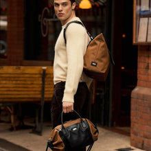 Load image into Gallery viewer, Man carrying The Gallery Duffel Bag aoife® color Brown and Black made with ECONYL® regenerated nylon
