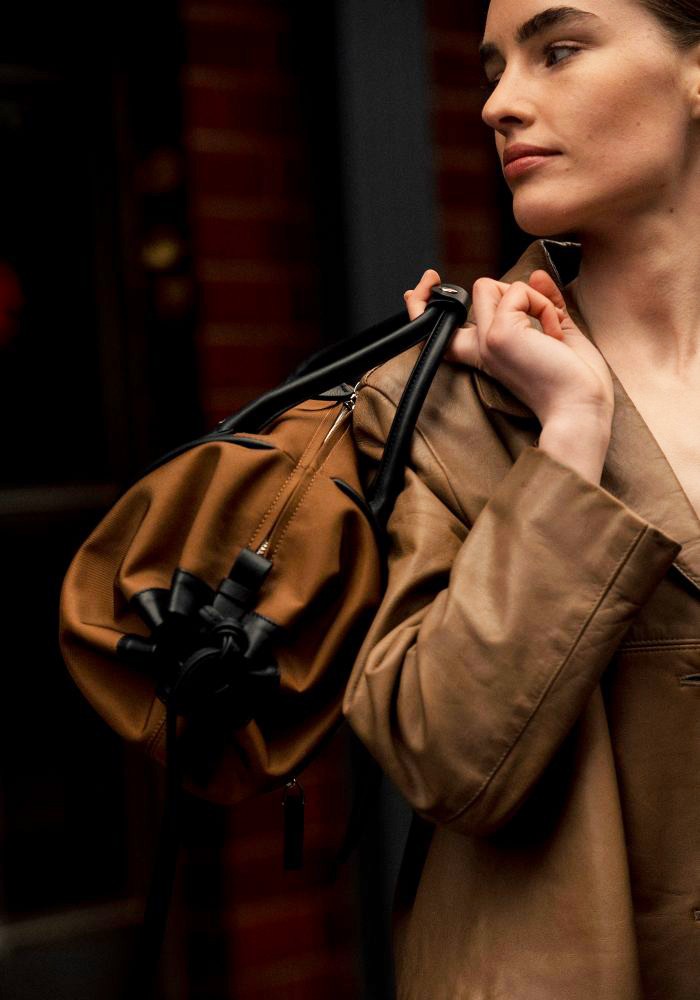 Detail of a woman carrying The Gallery Duffel Bag aoife® color Brown made with ECONYL® regenerated nylon