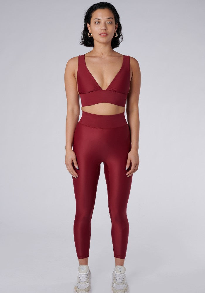 Front view of a woman wearing the Cora Leggings Wine by Outfyt color Red made with ECONYL® regenerated nylon