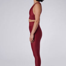 Load image into Gallery viewer, Side view of a woman wearing the Cora Leggings Wine by Outfyt color Red made with ECONYL® regenerated nylon
