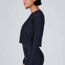 Load image into Gallery viewer, Side view of a woman wearing the Elin Long Sleeve Crop by Outfyt color Black made with ECONYL® regenerated nylon
