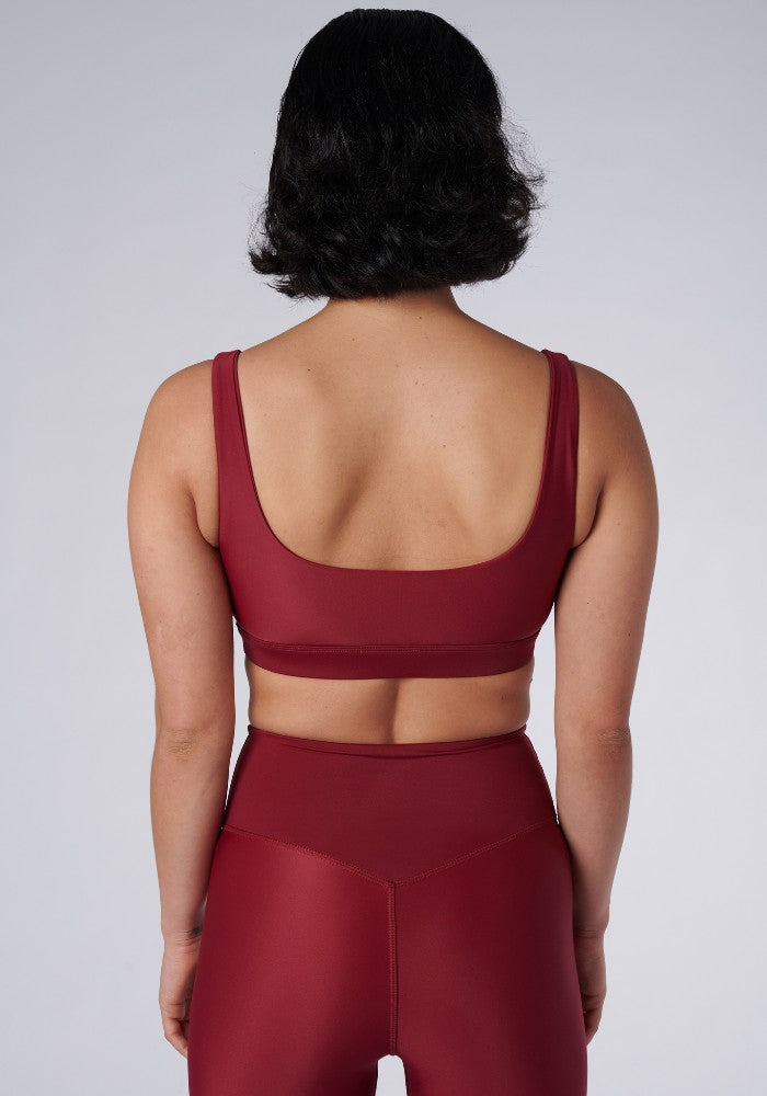 Back view of a woman wearing the Mera Sports Bra Wine by Outfyt color Red made with ECONYL® regenerated nylon