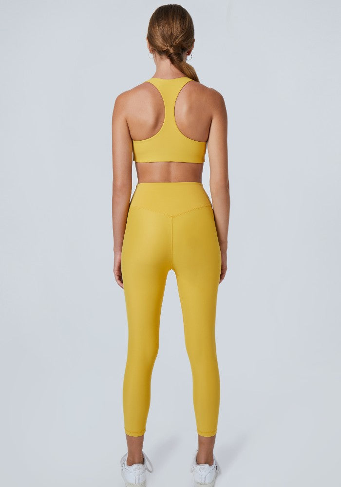 Back view of a woman wearing the Mila Leggings Mustard by Outfyt color Yellow made with ECONYL® regenerated nylon