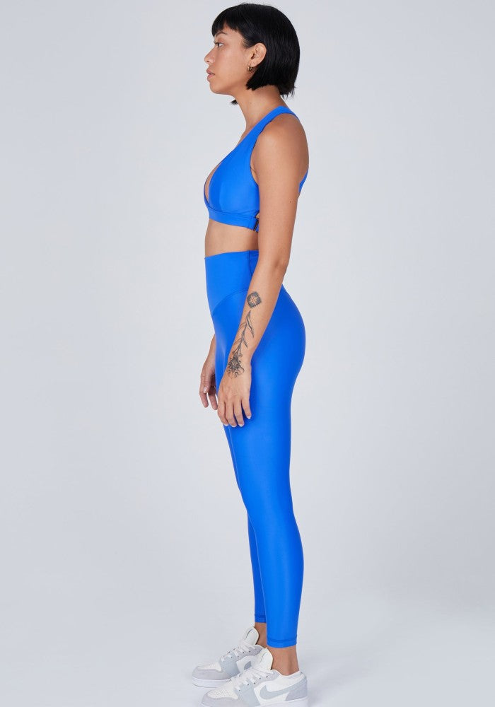 Side view of a woman wearing the Sage Leggings Lapis by Outfyt color Blue made with ECONYL® regenerated nylon