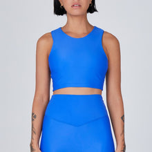 Load image into Gallery viewer, Front view of a woman wearing the Tula Crop Top Lapis by Outfyt color Blue made with ECONYL® regenerated nylon
