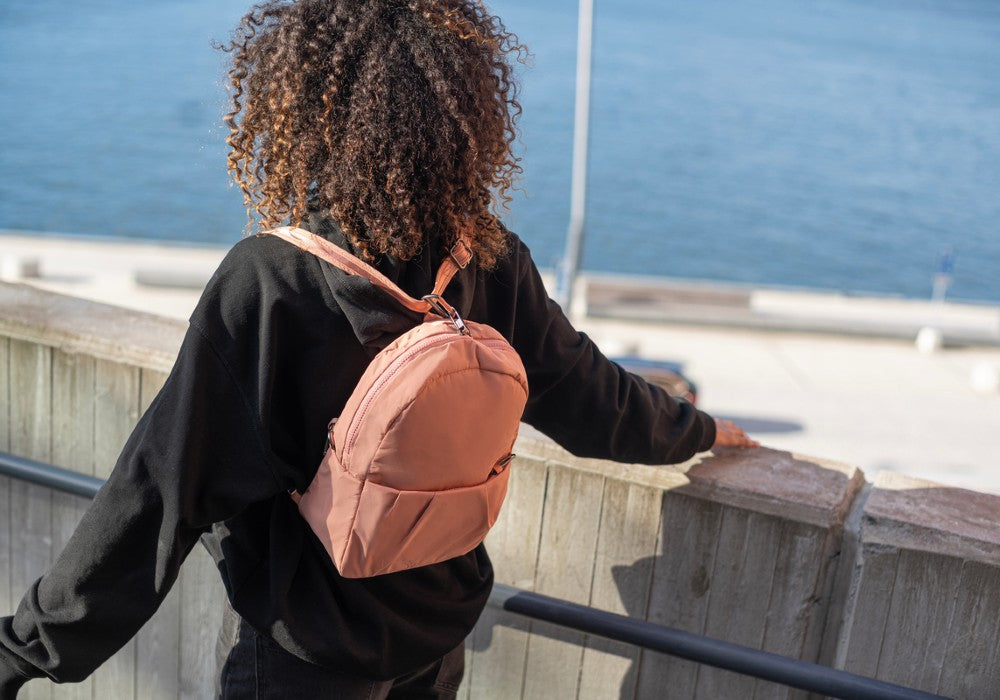 Woman travelling with the Pacsafe Citysafe CX Anti-Theft Convertible Backpack color Rose made with ECONYL® regenerated nylon