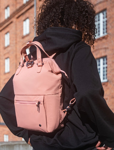 Woman travelling with the Pacsafe Citysafe CX Anti-Theft Mini Backpack color Rose made with ECONYL® regenerated nylon