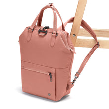 Load image into Gallery viewer, Side view of the Pacsafe Citysafe CX Anti-Theft Mini Backpack color Rose made with ECONYL® regenerated nylon locked to a chair
