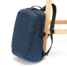 Load image into Gallery viewer, Side view of the Pacsafe Vibe 25L Anti-Theft Backpack color Ocean made with ECONYL® regenerated nylon locked to a chair
