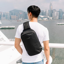 Load image into Gallery viewer, Man travelling with the Pacsafe Vibe 325 Anti-Theft Sling Pack color Black made with ECONYL® regenerated nylon
